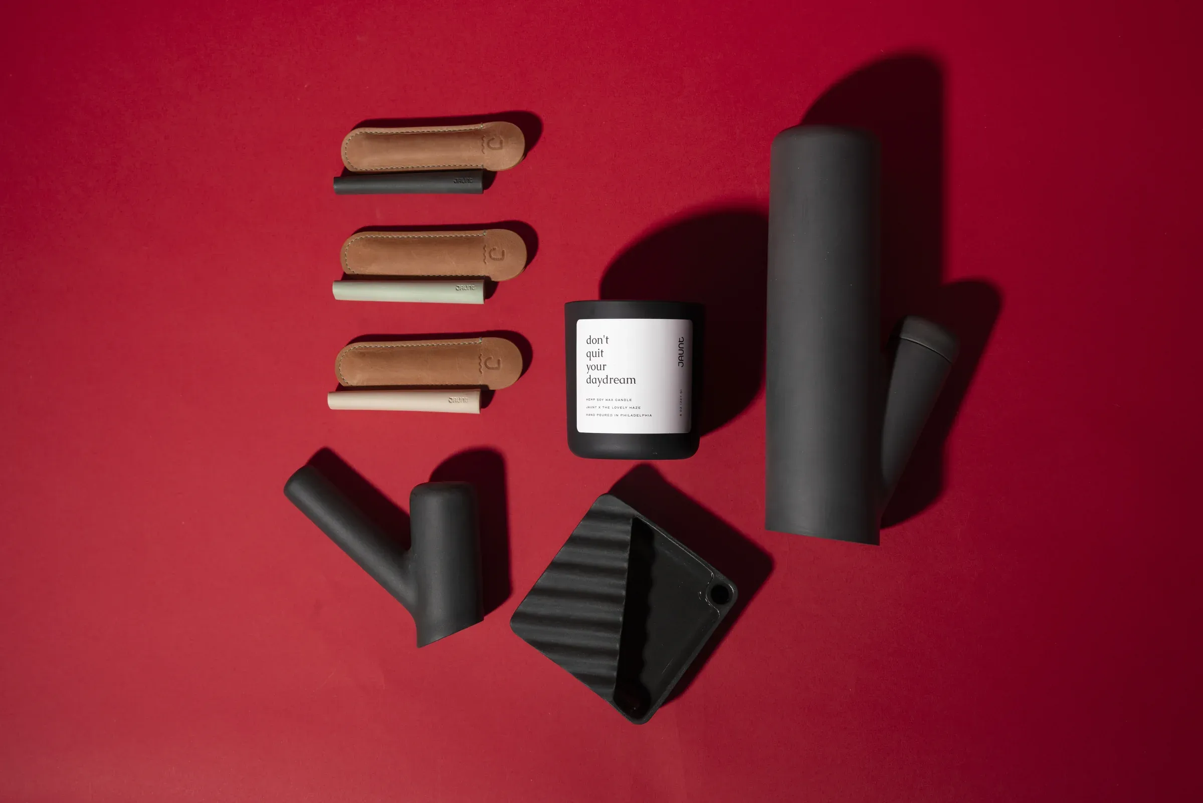 Smoking accessories and a candle arranged on a red background.