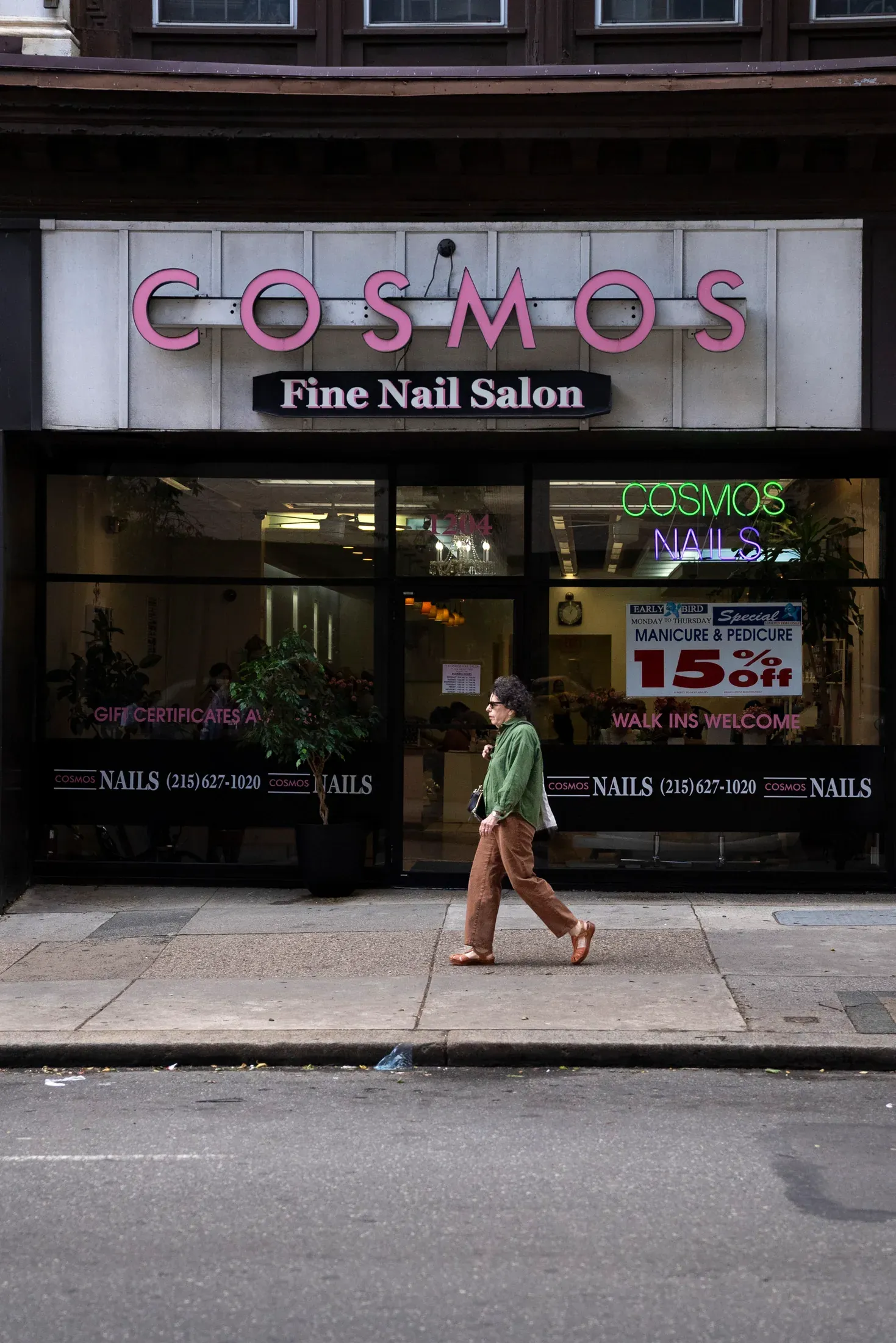 A pedestrian passing a neighborhood nail salon.