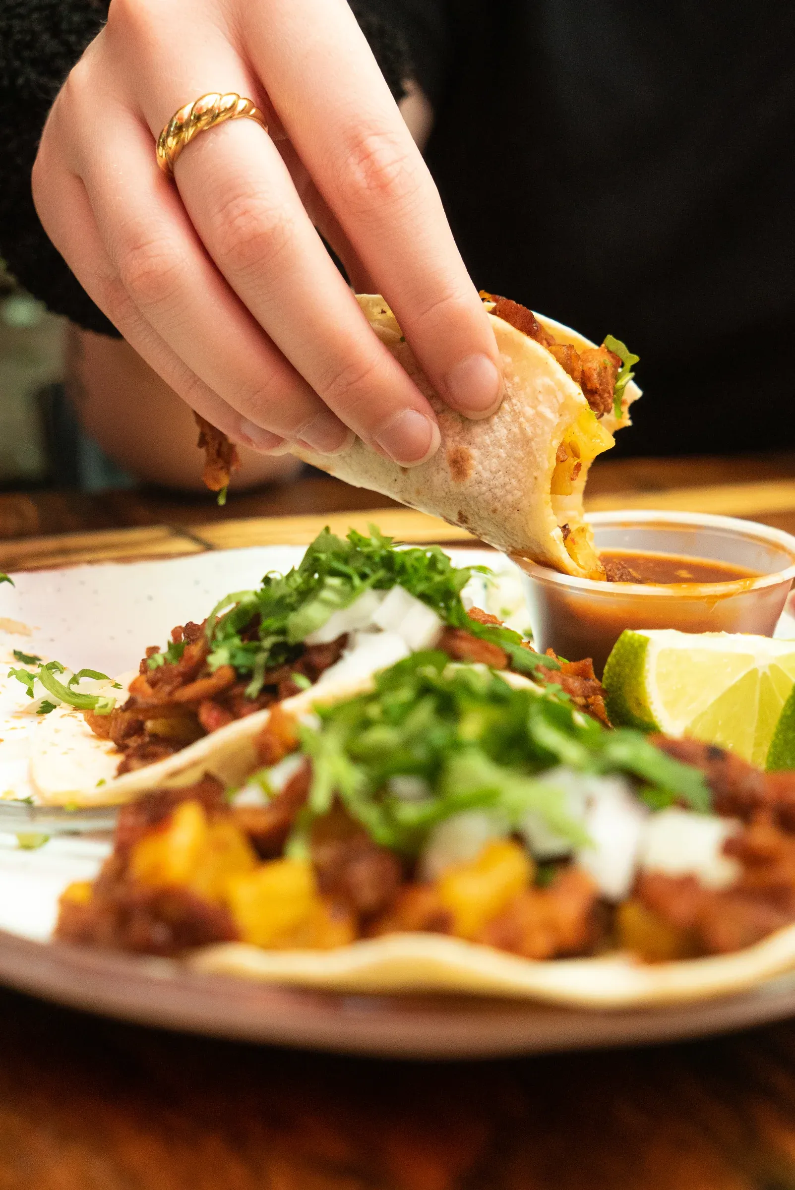 A diner reaching toward a plate of tacos at the table.