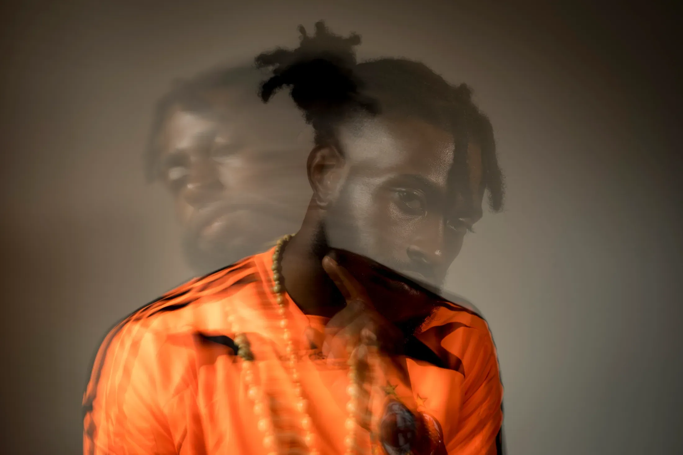 Double-exposure portrait of a man wearing an orange shirt.