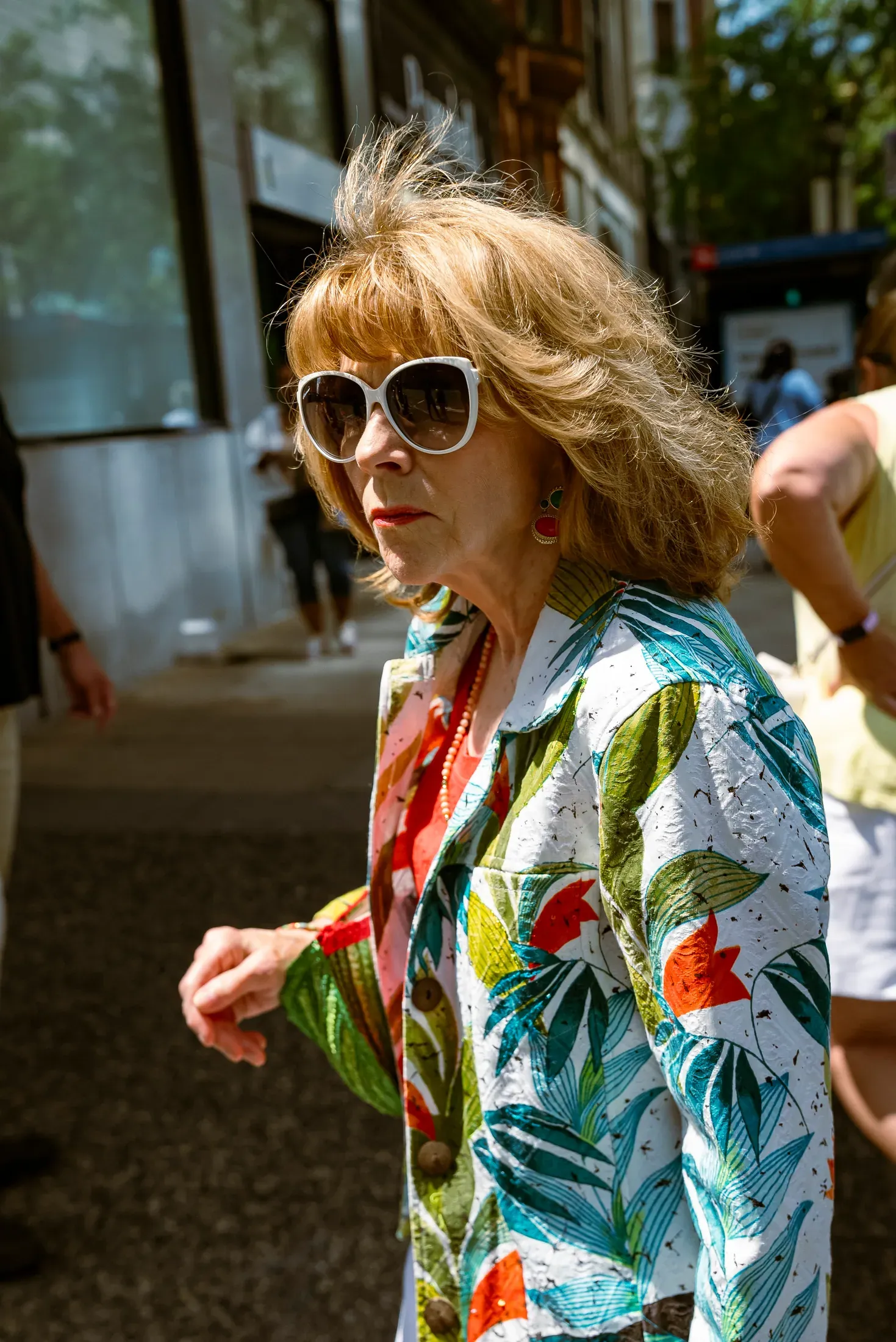 A woman in a floral shirt crossing a patch of sunlight.