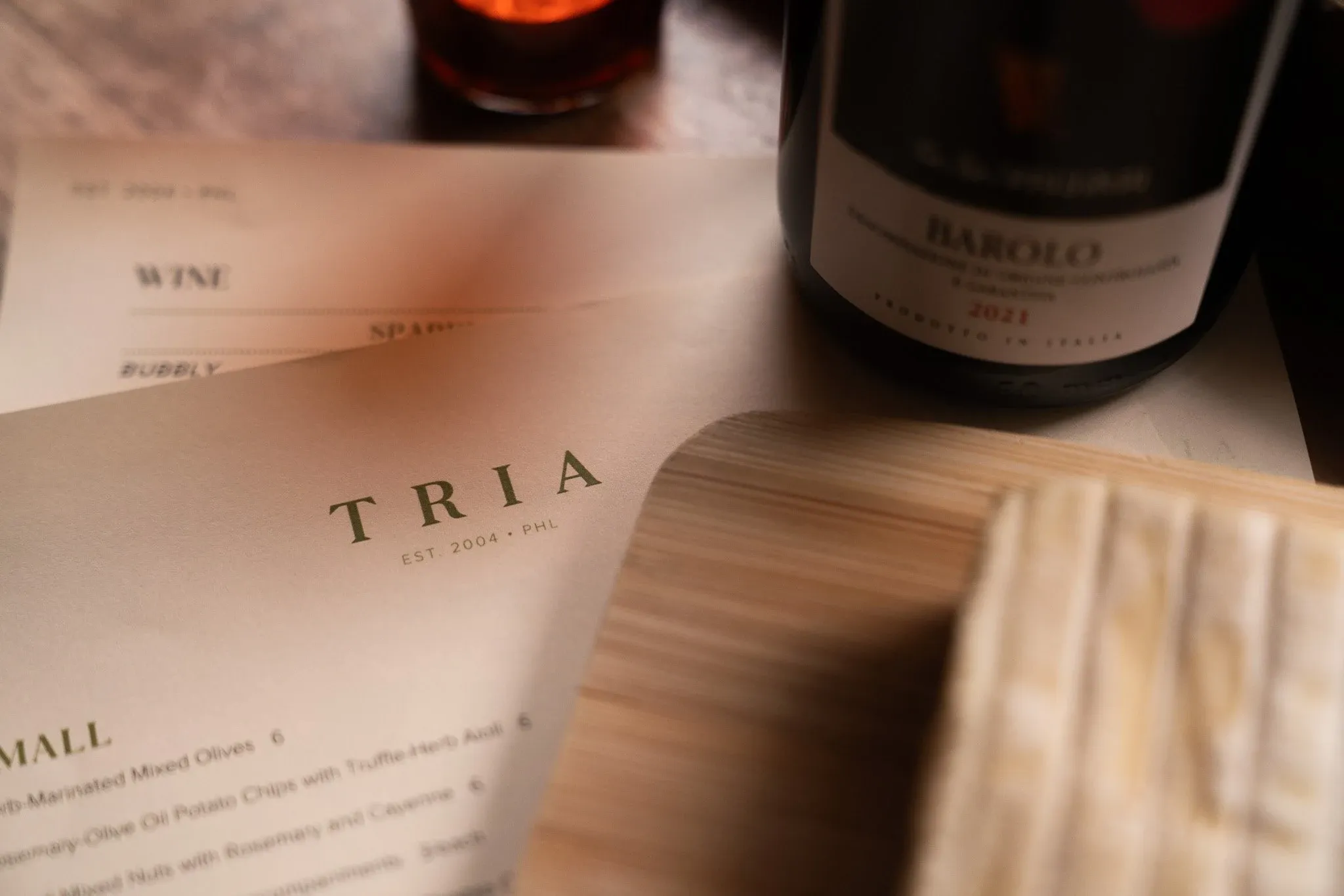 A bottle of wine, candlelight, and cheese photographed at Tria Wine Bar.