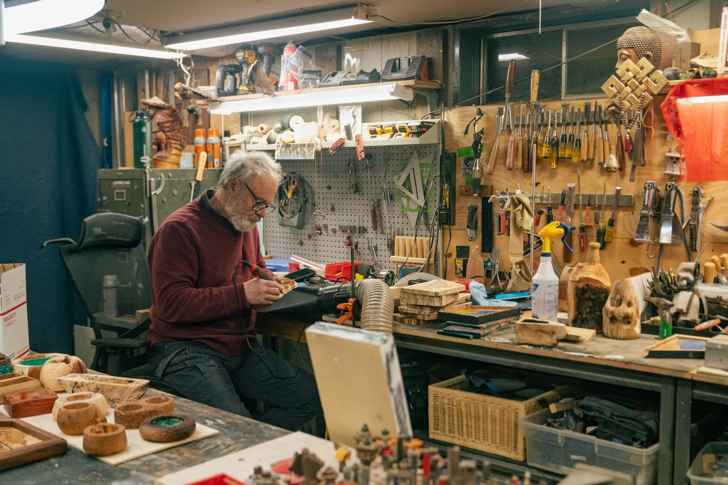 An artist working at a tool-filled bench.