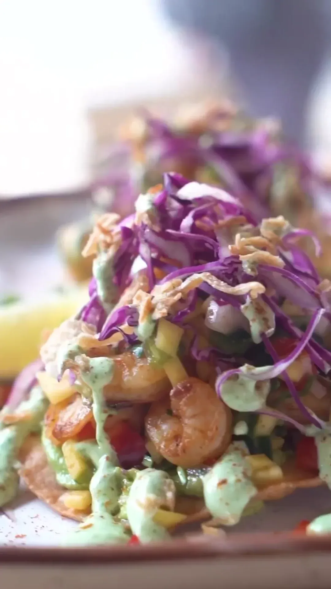 A colorful restaurant plate finished with purple cabbage and green sauce.