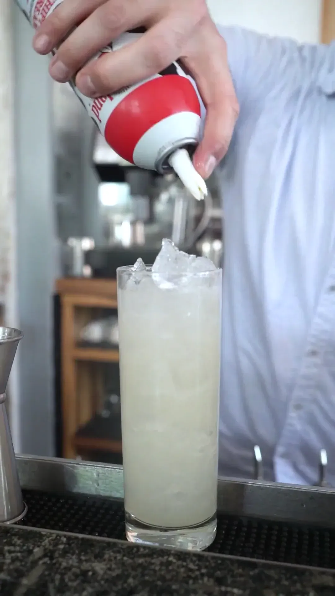 A bartender finishing a pale cocktail with whipped topping.