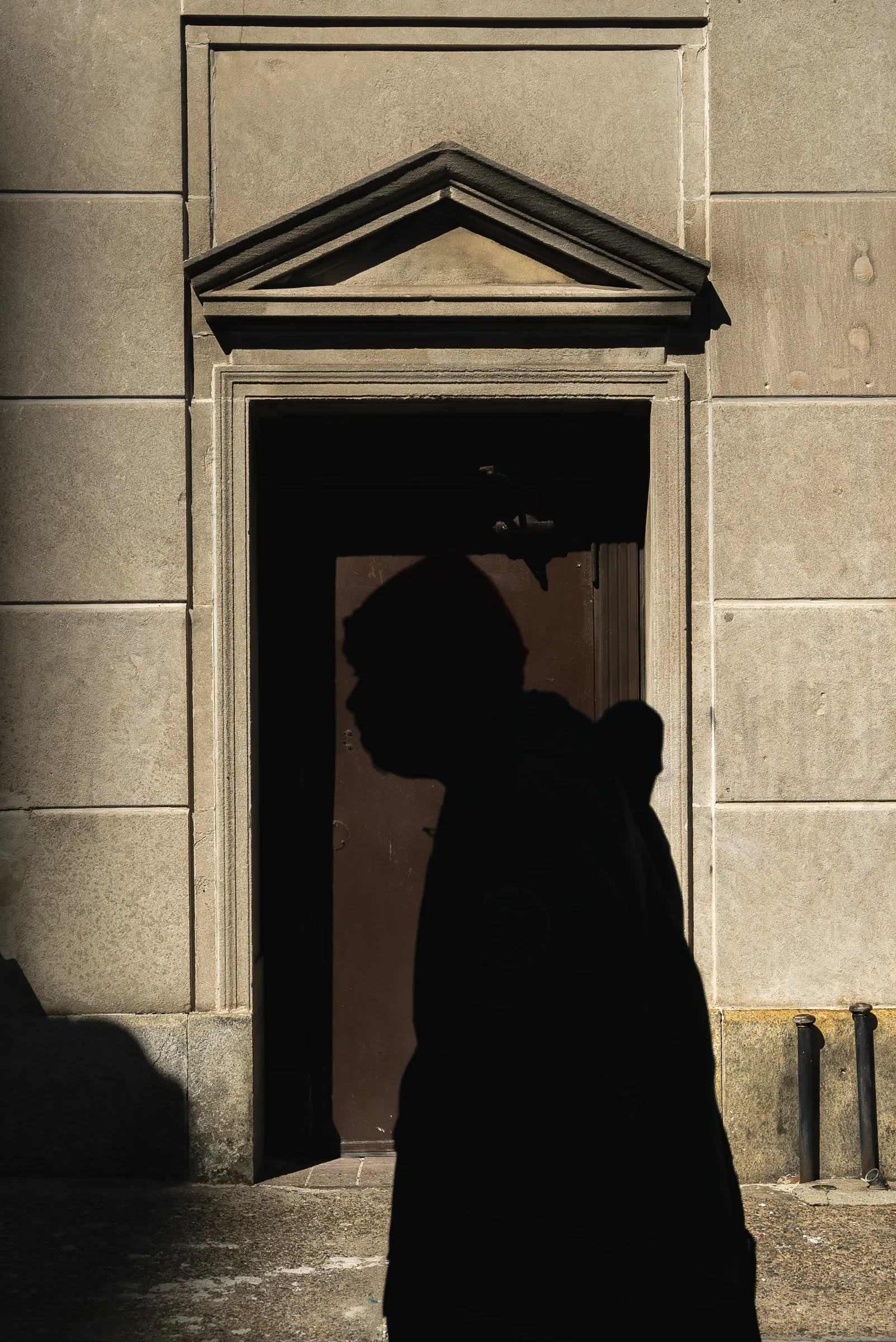 A person’s shadow crossing a sunlit doorway.
